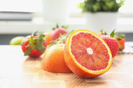 Close-up of yummy fresh summer grapefruit slices on cutting board, organic strawberry for cocktail. Vitaminized snack, nutritious. Eating, taste concept