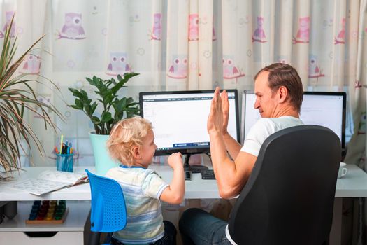 Father with kid trying to work from home during quarantine. Stay at home, work from home concept during coronavirus pandemic