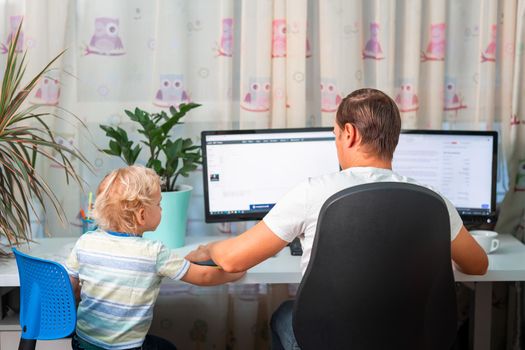 Father with kid trying to work from home during quarantine. Stay at home, work from home concept during coronavirus pandemic