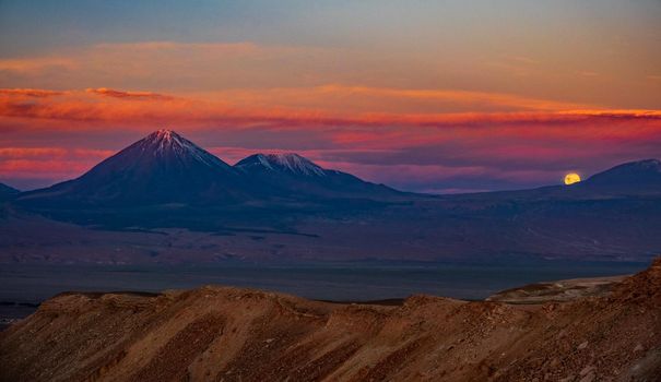 Moon rising over the mountains in Atacama desert with Licancabur volcano