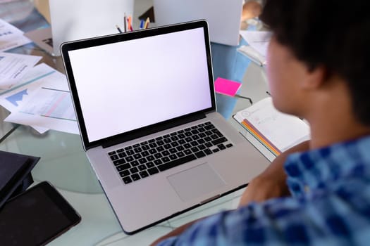 Multiracial businessman on laptop video call with copy space on blank screen. unaltered, home office, business, freelancer and technology concept.