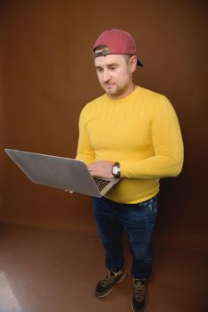 A man uses a laptop in the studio. Chubby man with his laptop stands in the studio.