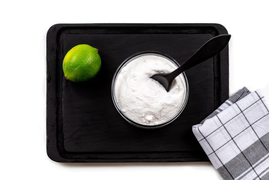 Saucer filled with bicarbonate with lime, placed on black board-Top view.