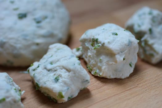 Raw dough pieces for pancakes with scallions on wooden board