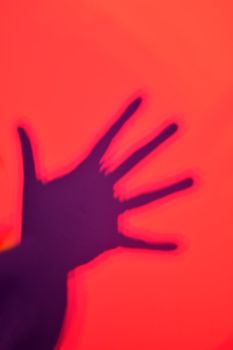 Distorted hand shadow on red background