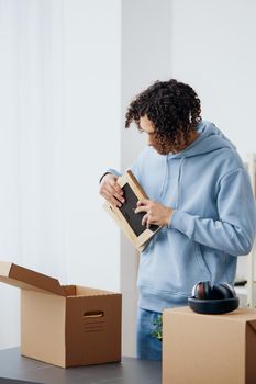 A young man cardboard boxes in the room unpacking sorting things out. High quality photo