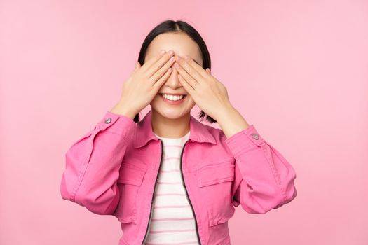 Surprise and celebration. Portrait of asian happy girl close eyes, waiting for gift, anticipating something, standing blindsided against studio background. Copy space