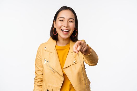 Congratulations, its you. Happy beautiful asian woman laughing, pointing finger at camera, choosing, inviting people, recruiting, standing over white background.