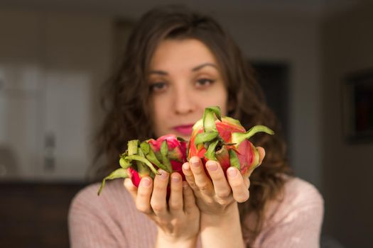 Young girl is holding two fresh ripe organic dragon fruits or pitaya, pitahaya. Exotic fruits, healthy eating concept.