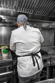 Back view of woman chef cooking food in the kitchen of a restaurant. High quality photography.