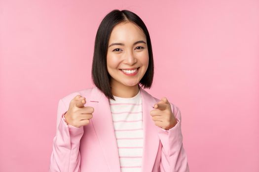 Its you, congrats. Smiling enthusiastic korean corporate lady, businesswoman pointing fingers at camera congratulating, praising you, standing over pink background.