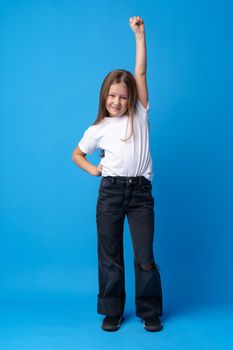 Little cute girl showing her strength on blue background, close up