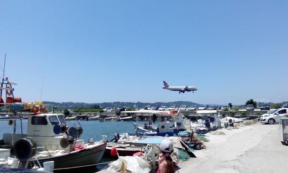 the concept of relaxing by the sea on a warm sand with the sound of the music of the waves begins in flight through the air on an airplane and landing at the airport in the photo a view of a landing plane against the background of a sea harbor. High quality photo