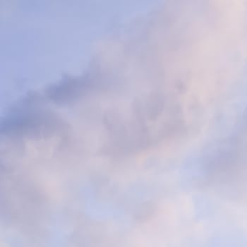 Background of blue sky with white and pink clouds at sunset. Natural backdrop