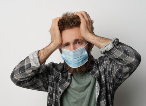 Sick young man in medical face mask feel migraine holding head. Handsome guy feel pain or headache. Exhausted young man trying to concentrate massaging his head. Health care concept. Covid 19 concept.