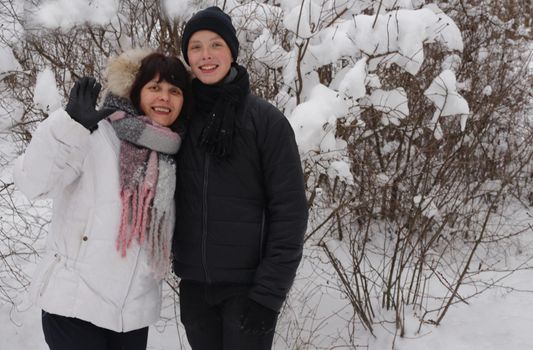 family outdoors. cheerful mommy with her child. Mother and son hugging in a park in winter against a backdrop of snow.