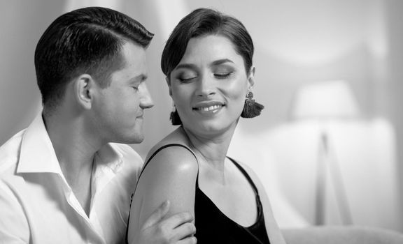 Beautiful young couple in home interior. Romance in relationships, love and tenderness. Husband and wife after a romantic dinner. Black and white photo.