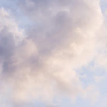 Background of blue sky with white and pink clouds at sunset. Natural backdrop