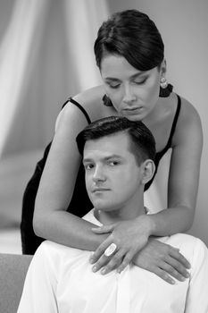 Young romantic couple is laughing sitting on the sofa in a cosy bedroom. They are in love with each other. The concept of love and tenderness. Black and white photography.