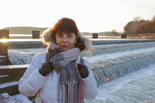 Woman against the background of a water landscape looking at the camera.