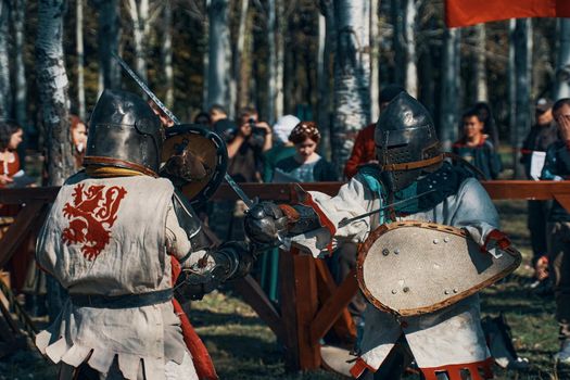 Battle of knights in armor on swords in front of the audience. Festival of historical clubs in the Park. Reconstruction of medieval battles. Bishkek, Kyrgyzstan - October 13, 2019