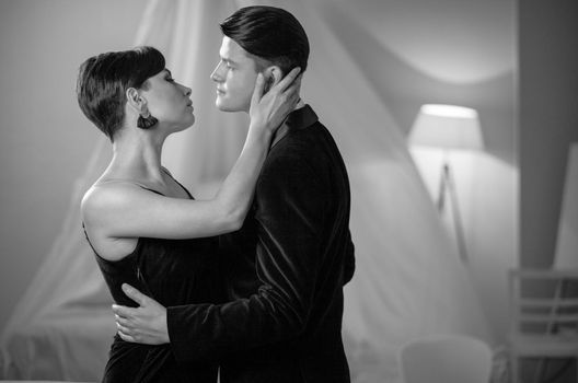 Portrait of dancing beautiful young couple in home interior. Romance in relationships, love and tenderness. Husband and wife after a romantic dinner. Black and white photo.