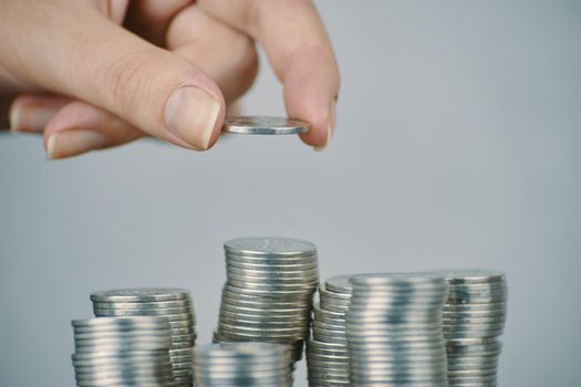 Hand put silver money coins to one of stacks. Expenses and earnings. Different growth of infographics. Concept of business planning and finance. Alms and donations. Small savings.