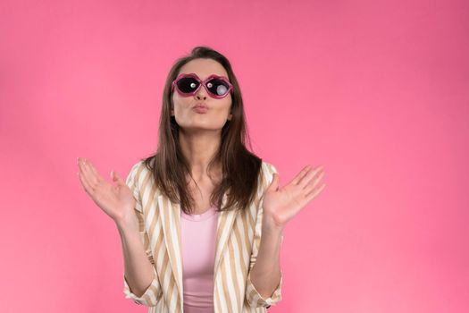 Suffering of headache or migraine young woman in sleeveless pink t-shirt holding her head with eyes shut isolated on pink background. Stressed employee woman in stripe suit. With copy space.