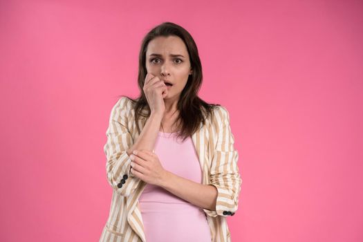 Suffering of headache or migraine young woman in sleeveless pink t-shirt holding her head with eyes shut isolated on pink background. Stressed employee woman in stripe suit. With copy space.