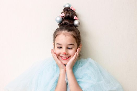 Portrait with a funny emotion, a beautiful little girl in blue clothes, with a haircut in the form of a Christmas tree with a luminous garland