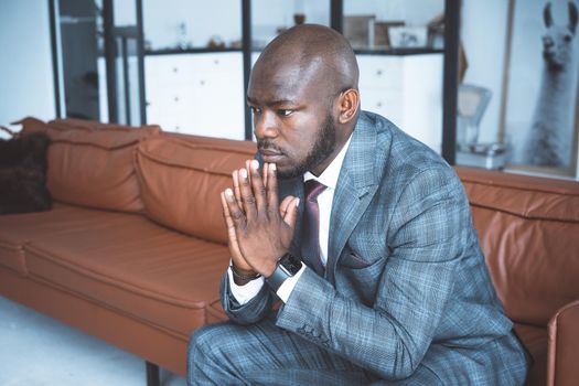 Businessman Pondering of Business Development Strategies. Handsome Man in Classic Suit Sits on a Leather Sofa in the Hall of his Modern Office. Close-up. High quality photo