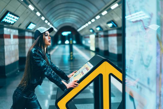 Fashion Style Model Female Of 20s Posing on Subway Station Platform. Gorgeous Brunette Woman Looks at the Metro Map in the Platform of the Empty Station. Close-up. High quality photo