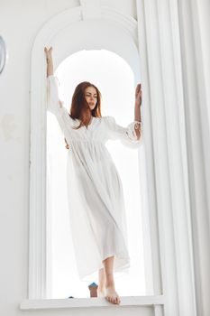 Woman in white dress near window light sun. High quality photo