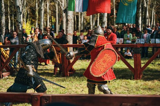 Battle of knights in the arena. Swords, shields, helmets and armor on the knights. Reconstruction of medieval battles. Festival of medieval culture. Bishkek, Kyrgyzstan - October 13, 2019