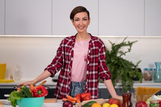 Cutting ingredients on table young woman cooking a lunch standing in the kitchen. Healthy food living. Healthy lifestyle. Cooking at home for loving family.