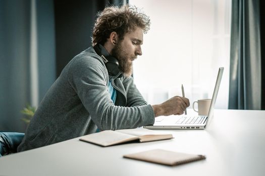 Handsome Guy Makes an Order of Goods in Online Store From His Laptop. Man Chooses Home Delivery From the Supermarket. Close-up. High quality photo