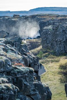 Thingvellir fault with tourists walking and waterfall in Iceland