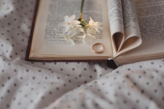 Golden ring and open book with folded sheets in heart shape. Wedding concept, Valentines Day.