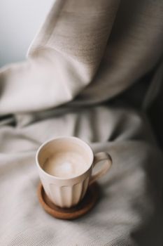 Cup of coffee with milk on beige plaid