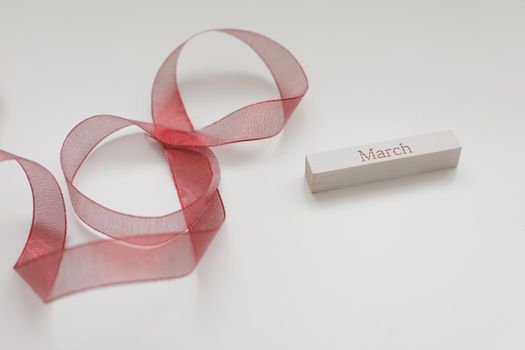 8 March, International Women's Day concept. Red ribbon and word MARCH on white background. 