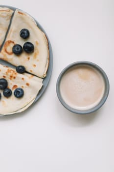 Pancakes with blueberries on a white table with a coffee cup