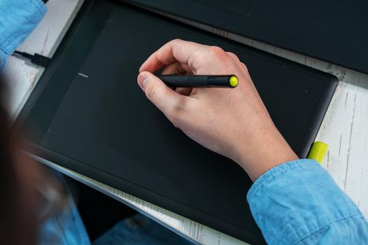 designer working on a professional tablet with a pen, Close-up of a man's hand holding a graphic pen for drawing