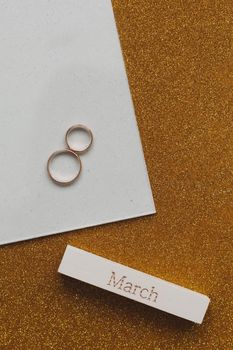  Eight made of two gold wedding rings and word MARCH. Greeting card for March 8. Flat lay, top view, copy space