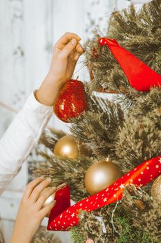 children's hands hang a decorative red ball on a branch of a New Year tree. New Years Eve, Midnight. Close-up. High quality photo