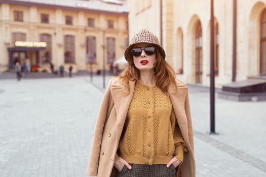 Young pretty french styled woman wearing sunglasses at camera. Stylish female tourist standing at the old city center. Tinted photo.