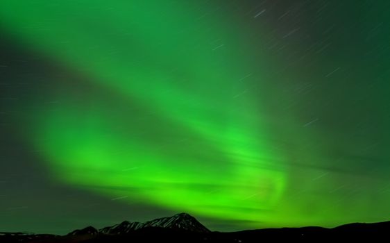 Aurora borealis star trail and mountain peak