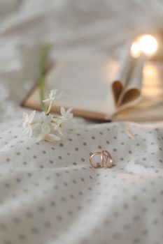 Golden ring and open book with folded sheets in heart shape in bed. Wedding concept, Happy Valentine's Day.