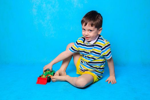 A boy is playing a typewriter on a blue background . An article about children's leisure. Children's games. Children's cars. Copy Space