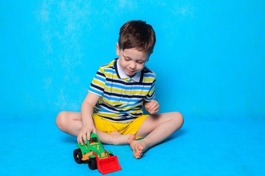 A boy is playing a typewriter on a blue background . An article about children's leisure. Children's games. Children's cars. Copy Space