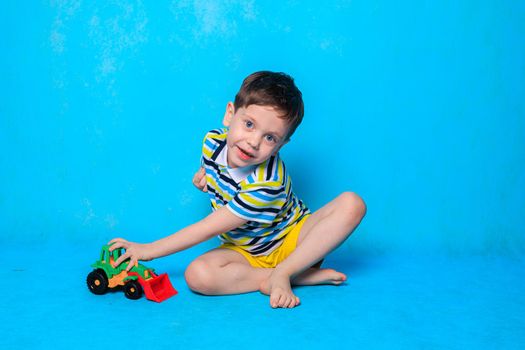 A boy is playing a typewriter on a blue background . An article about children's leisure. Children's games. Children's cars. Copy Space